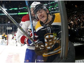In this photo taken with a fisheye lens, Bruins' Ryan Donato, front, is checked into the boards by Montreal Canadiens' Nicolas Deslauriers on Saturday, Oct. 27, 2018, in Boston.