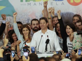 Flanked by his wife, Ana Estela, left, and running mate, Manuela d'Avila, Workers' Party presidential candidate Fernando Haddad pauses during his concession speech while his staff and supporters cheer him on, in Sao Paulo, Brazil, Sunday, Oct. 28, 2018. Brazil’s Supreme Electoral Tribunal declared far-right congressman Jair Bolsonaro the next president of Latin America’s largest country.