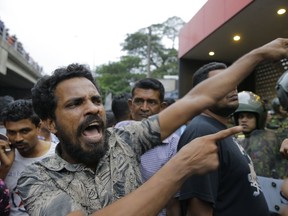 A supporter of newly appointed Sri Lankan prime minister Mahinda Rajapaksa shouts at police officers outside petroleum ministry building in Colombo, Sri Lanka, Sunday, Oct. 28, 2018. Arjuna Ranatunga who was petroleum minister under Wickremesinghe said one of his security guards opened fire when Rajapaksa supporters mobbed him and protested against him entering the ministry premises.