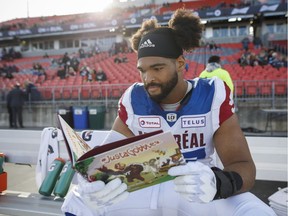 Montreal Alouettes defensive tackle Woody Baron poses with his children's book on the sidelines in Toronto Oct. 20, 2018.