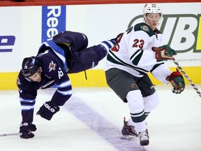 Winnipeg Jets' Andrew Ladd (16) goes over the back of Minnesota Wild's Gustav Olofsson (23) during first period pre-season NHL hockey action at MTS Centre in Winnipeg Sept. 22, 2014.