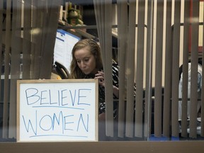 A Capitol Hill staff member puts up a sign that reads "Believe Women" as she looks out her office window at a group of protesters against Supreme Court nominee Brett Kavanaugh Sept. 24, 2018.