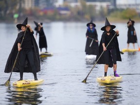 Hundreds of witches, along with a handful of warlocks and wizards, tossed their broomsticks, grabbed paddles and traveled six miles along the Willamette River Saturday, Oct. 27, 2018. The event, called Standup Paddleboard Witch Paddle, dodged days of rain catching a short window of sunshine for the entire three-hour event. The costumed coven cruised for six miles along the Willamette River, which divides the city of Portland.  (Mark Graves/The Oregonian via AP) ORG XMIT: ORPOR101