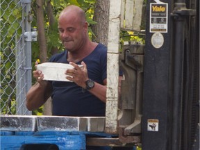 A Montreal police investigator lifts one of the silver ingots recovered in the Pointe-Claire area in 2015. (John Kenney / MONTREAL GAZETTE)