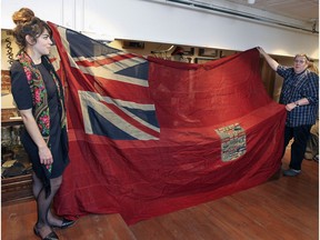 Curator Caitlin Bailey and collector Mark Cahill unfold a red ensign, the Canadian flag during World War 1, at Cahill's Canadian Centre for the Great War, in 2015.