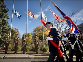 Veterans march past flags flown at half staff in front of the cenotaph, monument erected in memory of fallen soldiers, beside Pointe-Claire City Hall, on Sunday, Nov. 4, 2018.