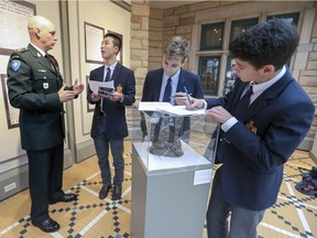 Honorary Lieutenant-Colonel Colin Robinson of the Royal Montreal Regiment speaks to Lower Canada College grade 10 history student Jiaxhan Li  while classmates Manu Boucher and Matthew Anzarouth, right, fill out a class worksheet while visiting World War I exhibit at Westmount's Victoria Hall in Montreal Wednesday November 7, 2018.