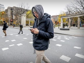 Corentin Le Goff writes a text message while crossing Sherbrooke St. in downtown Montreal on Friday, Nov. 9, 2018.