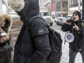 A man wearing a Canada Goose parka with his hood up walks past PETA protester Len Goldberg on Friday, Nov. 16, 2018, the Peel and Ste-Catherine Sts. store's grand opening.