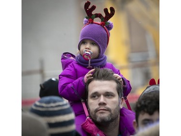 Two-year-old Chloe Rouzier and her father,  Edouard, wait for Santa to appear during the parade along Ste-Catherine St. in Montreal on Saturday, Nov. 17, 2018.