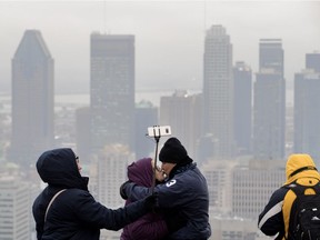 Yaritza Casillas takes a picture as Angel and Nelida Casillas kiss during a visit to the Mount Royal Chalet under a dark gloomy sky in Montreal in November 2018.