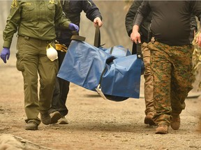 TOPSHOT - Rescue workers carry a body away from a burned property in the Holly Hills area of Paradise, California on November 14, 2018. - Firefighters backed by air tankers and helicopters battled California's raging wildfires for a seventh day on Wednesday as the authorities in the worst-hit county released a list of over 100 missing people. At least 51 deaths have been reported so far from the deadliest wildfires in California's recent history and body recovery teams were going house-to-house with cadaver dogs in Paradise.