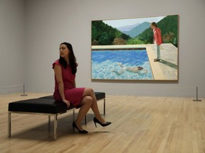 FILE - In this Feb. 6, 2017, file photo, a Tate representative poses for photographs next to British artist David Hockney's "Portrait of an Artist (Pool with Two Figures) during a photo call to promote the largest-ever retrospective of his work at Tate Britain gallery in London. The painting, considered one of Hockney's premier works, was sold at auction by Christie's in New York for $90.3 million.