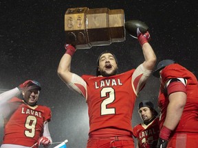 Laval Rouge et Or Adam Auclair celebrates with the RSEQ Championship Dunsmore Cup after defeating the Montreal Carabins at Laval University in Quebec City on Saturday, Nov. 10, 2018. Team captain Mathieu Betts, left, looks on.