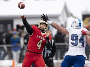 Laval Rouge et Or quarterback Hugo Richard throws a pass as Montreal Carabins Philippe Lemieux-Cardinal attempts to block during first half action of the Dunsmore Cup on Nov. 10, 2018, in Quebec City.