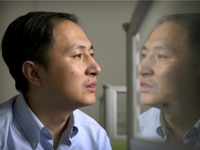 In this Oct. 10, 2018 photo, He Jiankui is reflected in a glass panel as he works at a computer at a laboratory in Shenzhen in southern China's Guangdong province.