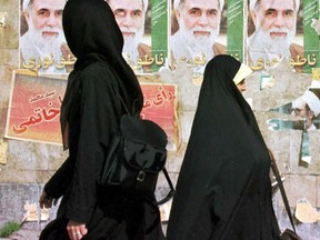 Iranian women in chadors walk past election posters in Tehran in 1997. "People can think that hijabs and chadors and niqabs are just pieces of clothing, but courageous Iranian women go to jail to live free of them," Lise Ravary writes.