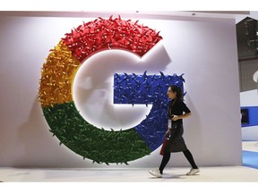 In this Monday, Nov. 5, 2018, photo, a woman carries a fire extinguisher past the logo for Google at the China International Import Expo in Shanghai. Internet traffic hijacking disrupted several Google services Monday, Nov. 12, 2018, including search and cloud-hosting services.