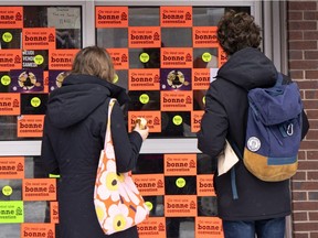 A couple read the notice on the door of a closed liquor store in Montreal on Friday, November 16, 2018. Unionized employees with the SAQ walked off the job Friday and will remain on strike until Monday.