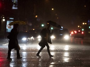 Pedestrians try to shield themselves from the rain as they cross Ontario St. in Montreal in this September 2018 file photo.