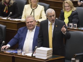 Vic Fedeli rises in the legislature in Toronto Nov. 15, 2018, to read the Economic Outlook for Ontario, as his fellow MPPs wear yellow to show their support for him.