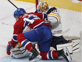 Canadiens' Max Domi falls on Buffalo Sabres goaltender Carter Hutton during overtime in Montreal on Nov. 8, 2018.