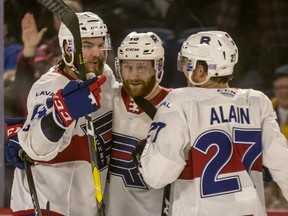 Laval Rocket defenceman Karl Alzner, centre, is congratulated by teammates Laval Rocket defenceman Brett Lernout (14) and Laval Rocket centre Alexandre Alain and (27) after Alzner scored his first Rocket goal of the season against the Belleville Senators at Place Bell in Laval on Nov. 28, 2018.