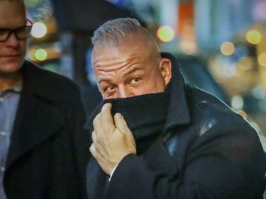 A guest covers his face from police and news photographers as he arrives for wedding of Hells Angel member Martin Robert to Annie Arbic in Montreal on Saturday, Dec. 1, 2018.