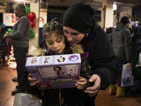 Scarlett Razouk, 6, looks at her new toy at the The Welcome Hall Mission in Montreal on Saturday, Dec. 1, 2018. The Welcome Hall Mission organized the largest toy giveaway in Quebec and toys were given to more than 2,700 kids. The Welcome Hall Mission has counted a growing number of asylum seekers among those it serves, including Rebecca, not pictured.