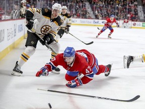 Montreal Canadiens' Kenny Agostino is checked to the ice by Boston Bruins John Moore during third period of National Hockey League game in Montreal Monday December 17, 2018.