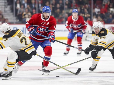 Paul Byron splits Boston Bruins' John Moore, left, and Noel Acciari as he crosses into Bruins territory during first period Monday, Dec. 17, 2018.