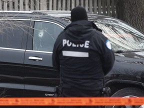 Montreal police officer stands next to SUV with bullet hole in passenger side window in St- Léonard on Thursday December 20, 2018.
