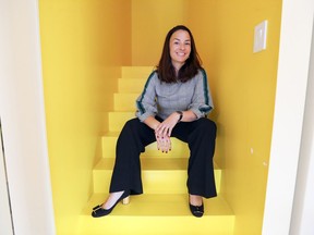 Vicky Boudreaux sits in the staircase  to the kitchen, painted yellow to create a cheery atmosphere for the morning walk down to the kitchen.