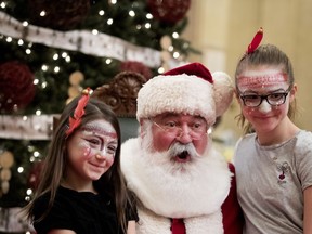 Leona Zummo Forgues, 8 yrs, left, and her sister Elina, 11, pose with Santa for pictures for their mother at city hall in Montreal on Saturday December 22, 2018. Mayor Valerie Plante worked independently of Santa this year, meet citizens privately in another room.