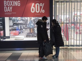 A man and woman wait outside a store during Boxing Day sales in Montreal Dec. 26, 2018.