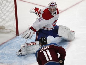 Montreal Canadiens goaltender Carey Price, back, makes a stop of a shot off the stick of Colorado Avalanche left wing Matt Calvert in the first period of an NHL hockey game Wednesday, Dec. 19, 2018, in Denver.
