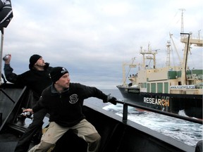 In this 2008 photo released by the Sea Shepherd Conservation Society, Australian crew member Ralph Lowe (left) and former Dutch police officer Laurens de Groot throw bottles of butyric acid from their own vessel Steve Irwin onto the Japanese whaler Nisshin Maru.