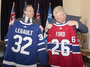 Quebec Premier Francois Legault, left, exchanges hockey jerseys with Ontario Premier Doug Ford at Queens Park, in Toronto on Monday, Nov. 19, 2018.