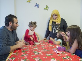 Syrian refugee family Mohammad Al Mnajer and wife Fouzia Al Hashish sit with their three daughters Judy, second left, Jaidaa, far right, and Baylasan as they eat their after school snack at their home in Mississauga, Ont., Thursday, Dec. 13, 2018.