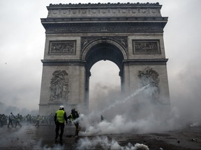 Demonstrators clash with riot police at the Arc de Triomphe during a protest of Yellow vests (Gilets jaunes) against rising oil prices and living costs on Saturday,  Dec. 1, 2018, in Paris.