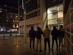 In this Nov. 9, 2018 photo, unaccompanied minors from Morocco seeking shelter, stand outside a police station in Barcelona, Spain. Slouched on a bench at a Barcelona police station, five teenagers waited patiently on a recent Friday evening to find out where they would sleep that night: a shelter for young migrants or on that bench.