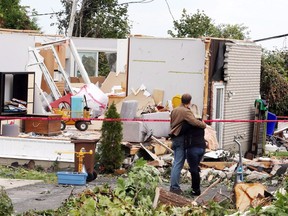A man and woman embrace as they survey the damage to a home in Gatineau Sept. 23, 2018. Houses and Apartment buildings had roofs torn off and windows blown out and automobiles were damaged after a tornado caused extensive damage.