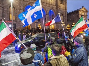 Mourners wave flags as the hearse leaves after funeral services for former Quebec premier Bernard Landry at Notre Dame Basilica in November.