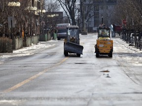 Snow removal crews speak for a moment while heading to refill with abrasives along Atwater St. in Montreal, Jan. 1, 2019.