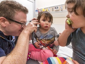Dr. Harley Eisman checks out 1-year-old Zoe Russo and her 2-year-old sister, Emma-Rose Russo, right, for the flu at the Montreal Children's Hospital.