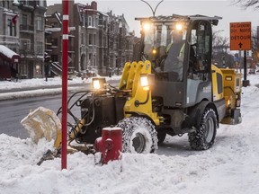 A worker clears snow from the sidewalk on René-Lévesque Blvd. in Montreal on Tuesday. The city is planning a full snow-clearing operation on Wednesday.