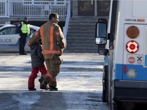 A firefighter walks a young student to a waiting STM bus after École des Découvreurs was evacuated on Jan. 14 because of a gas leak in the school.