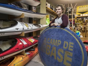 Camp de Base, an outdoors and paddle-sport store, is liquidating stock after going bankrupt. Austin Marsh of Continental Auctioneers holds the storefront sign in Pointe-Claire that was removed and signed by employees and customers alike.