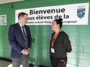 Riverdale High School principal Mat Canavan speaks with Marie Émond, responsible for the Riverdale and Lyndsay Place High School campuses of the Marguerite-Bourgeoys school board, by a welcoming poster in Riverdale in Pierrefonds.