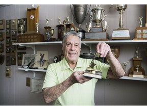 Wes Young, 85, poses with one of his hole-in-one trophies next to his golf trophy collection at his home in Roxboro on Saturday.